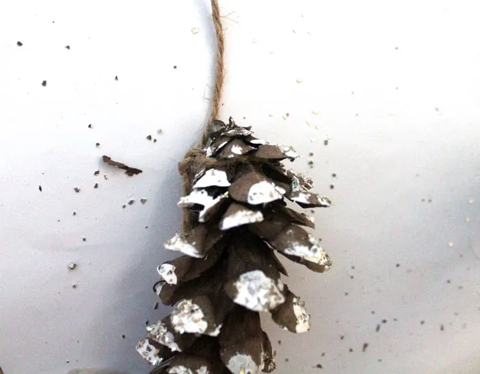 Make this beautiful snowy pine cone wall hanging! Such a pretty and easy winter craft to decorate your home. Plus, how to add a matching aroma to your decor!