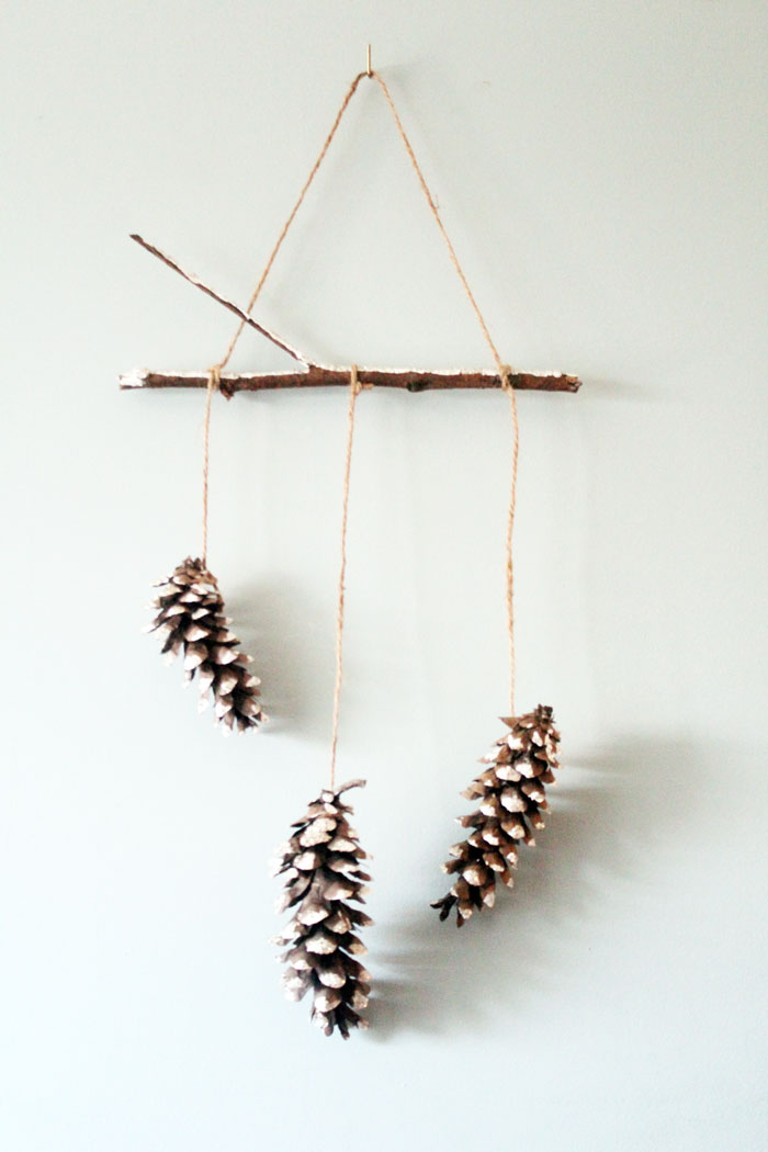 Make this beautiful snowy pine cone wall hanging! Such a pretty and easy winter craft to decorate your home. Plus, how to add a matching aroma to your decor!