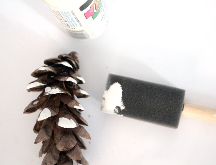 Make this beautiful snowy pine cone wall hanging! Such a pretty and easy winter craft to decorate your home. Plus, how to add a matching aroma to your decor!