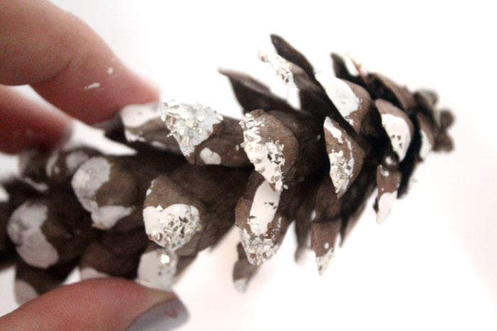 Make this beautiful snowy pine cone wall hanging! Such a pretty and easy winter craft to decorate your home. Plus, how to add a matching aroma to your decor!