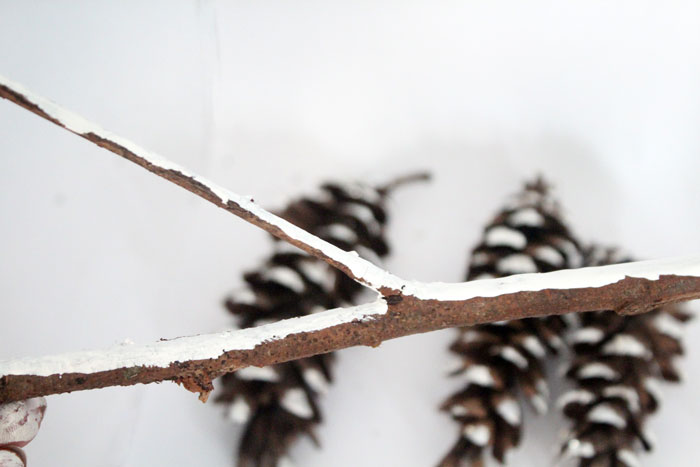 Make this beautiful snowy pine cone wall hanging! Such a pretty and easy winter craft to decorate your home. Plus, how to add a matching aroma to your decor!