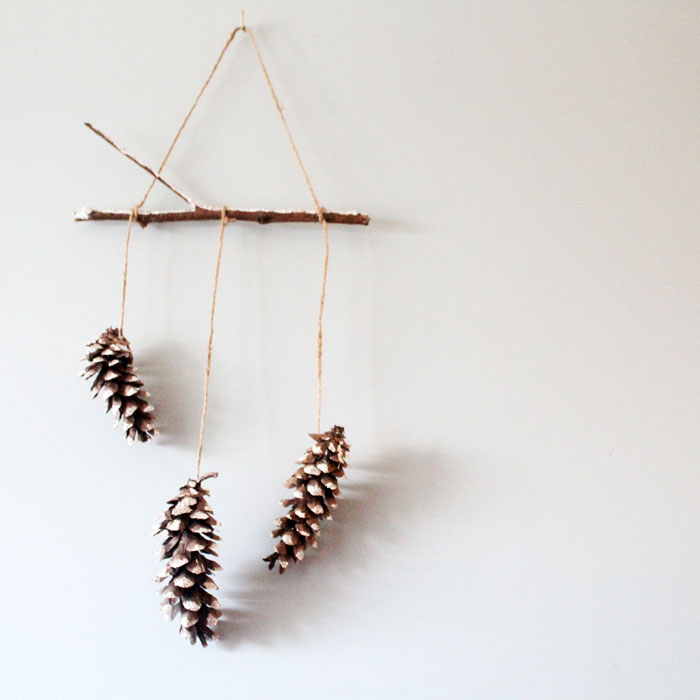 Make this beautiful snowy pine cone wall hanging! Such a pretty and easy winter craft to decorate your home. Plus, how to add a matching aroma to your decor!