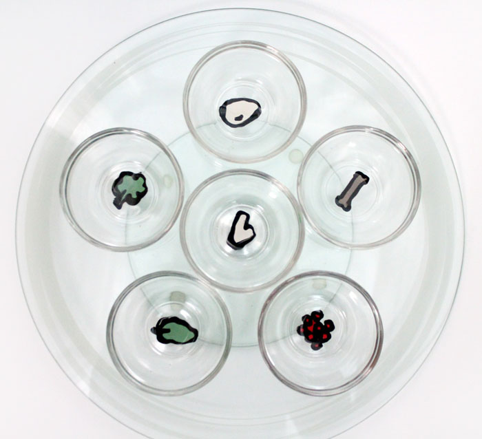 Make an easy DIY seder plate for Passover! This glass "ke'arah" plate is so easy to make and great if you are spending the Jewish holiday of Pesach by guests as it makes a great, portable gift (plus, it's super easy to make!)