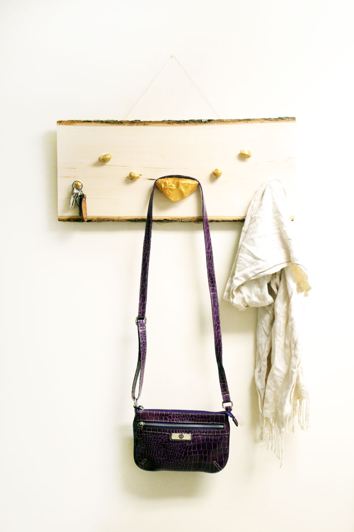 I LOVE how easy it is to make this DIY key and accessory organizer. What a great idea to declutter an entryway. IT will fit a rustic or natural home decor theme, with a touch of metallic gold too. Such a great entry organization idea - and it uses rocks, which are stuck WITHOUT TOOLS - how cool?!