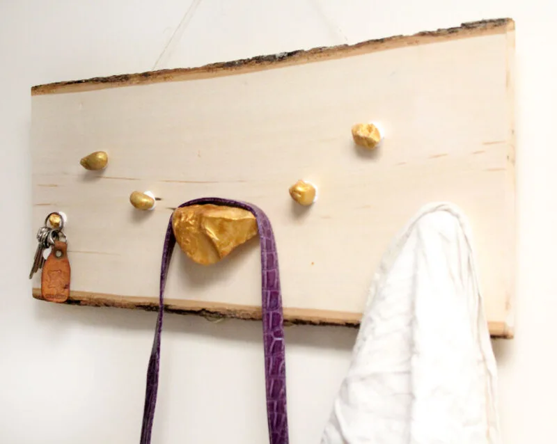 I LOVE how easy it is to make this DIY key and accessory organizer. What a great idea to declutter an entryway. IT will fit a rustic or natural home decor theme, with a touch of metallic gold too. Such a great entry organization idea - and it uses rocks, which are stuck WITHOUT TOOLS - how cool?!