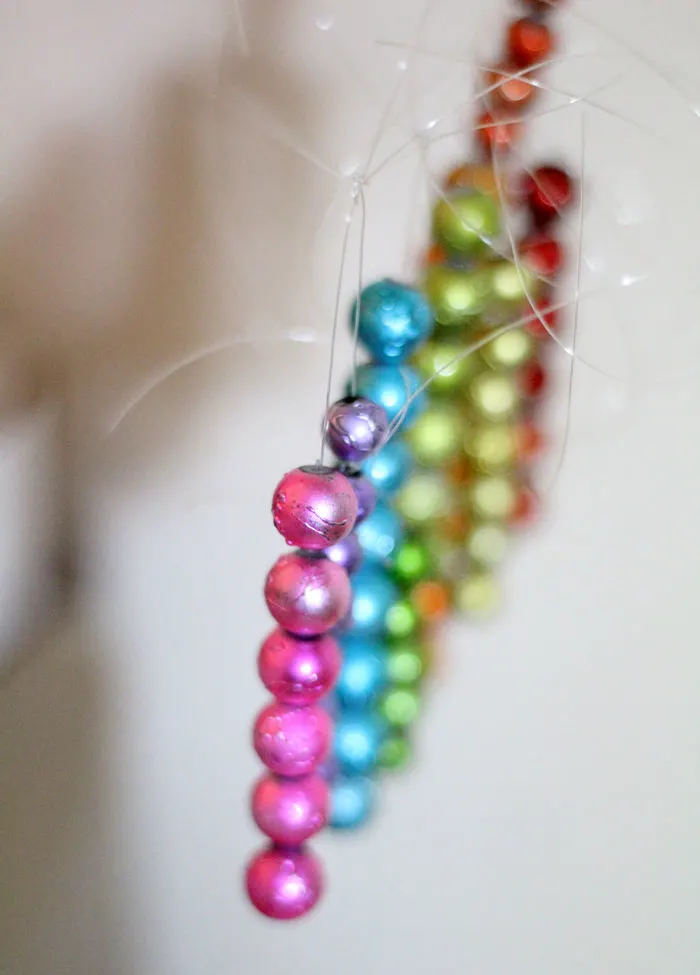 This beautiful DIY garland seems to disappear on the wall, leaving you with the hanging beaded strands! Such a cool effect. Make this easy beaded rainbow garland as a regular home decor staple or as a cool sukkah decoration craft.