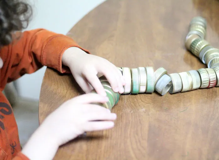 turn your recycling bin into a fun toy! Make a bottle cap rattlesnake craft for your little ones to play with - it actually rattles! This upcycled craft is a fun way to use up your bottle caps and a cute DIY toy idea.