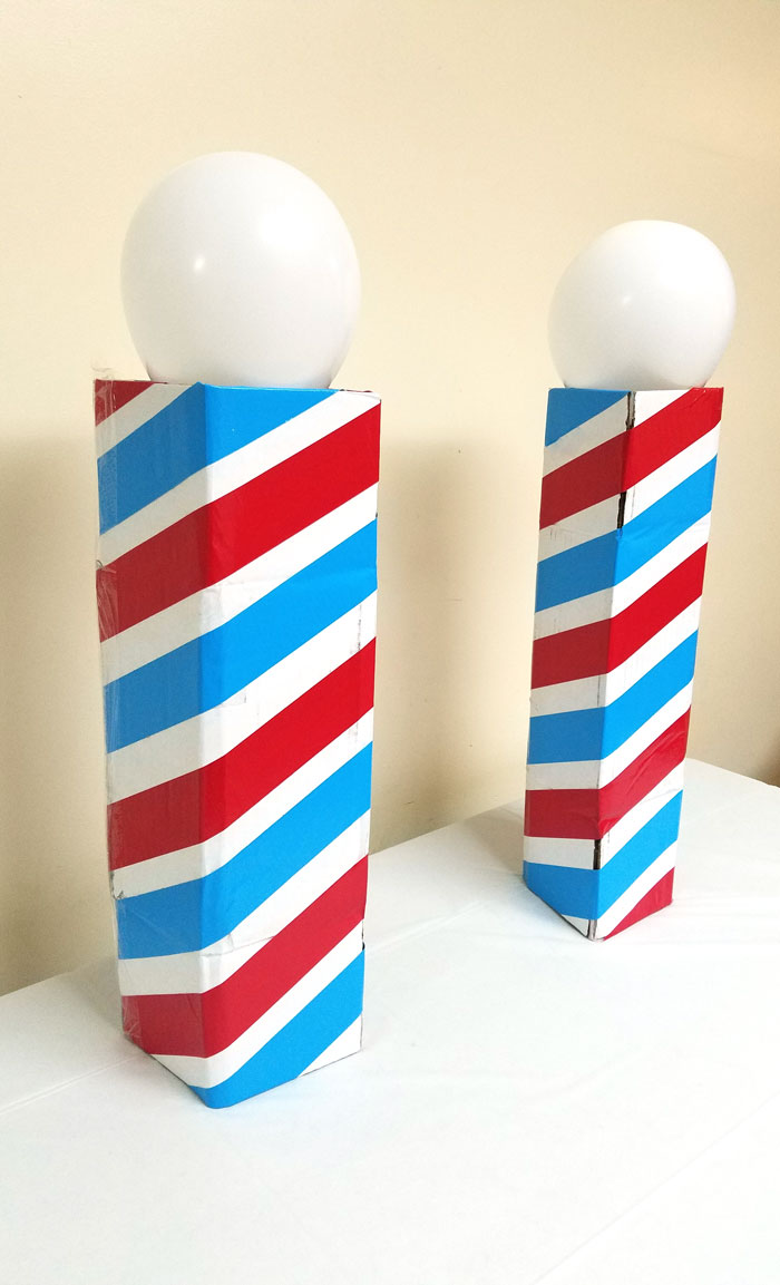 Make this barber shop pole centerpiece for you haircut party! This cool barber shop party decor idea is easy to make, mess-free, and uses recycled materials and is a great, easy upcycled cardboard box craft idea!