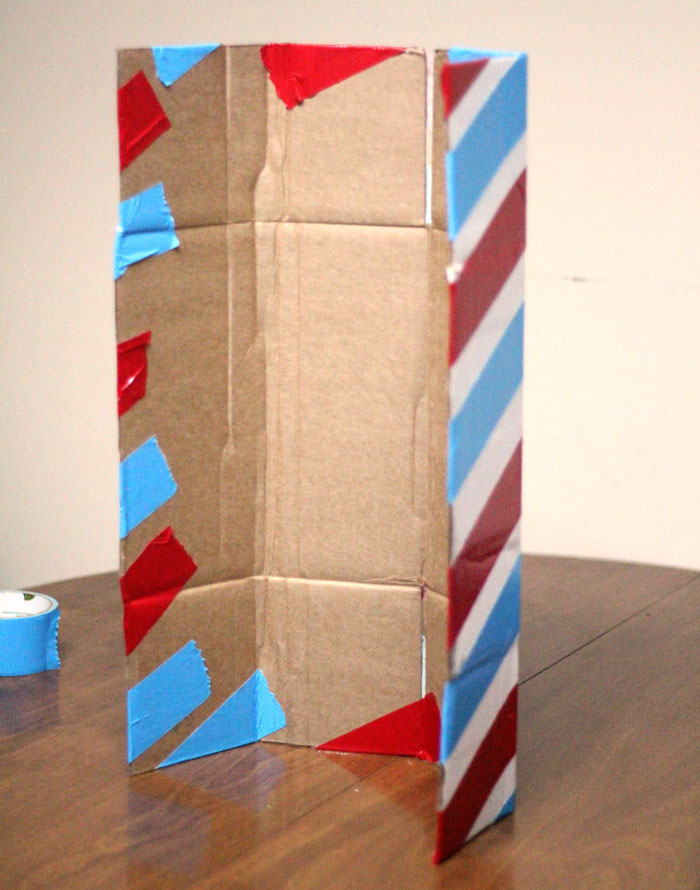 Make this barber shop pole centerpiece for you haircut party! This cool barber shop party decor idea is easy to make, mess-free, and uses recycled materials and is a great, easy upcycled cardboard box craft idea!