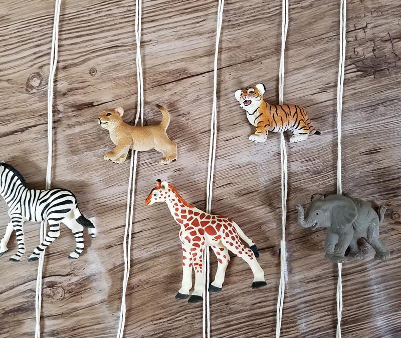 Make an adorable animal wall hanging for the kids room or nursery! Turn toy animals into beautiful playroom decor - and when your'e ready to redecorate, it can be repurposed as a toy! Love this safari animal kids bedroom decor idea - it's such an easy DIY decor craft!