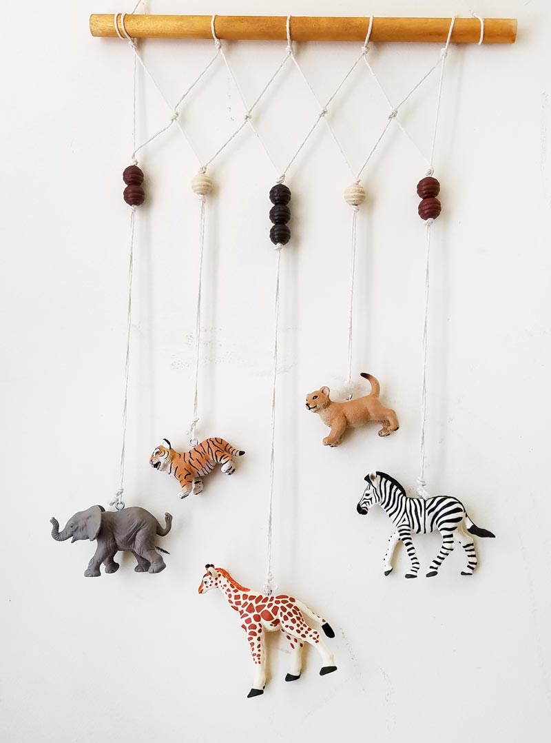 Make an adorable animal wall hanging for the kids room or nursery! Turn toy animals into beautiful playroom decor - and when your'e ready to redecorate, it can be repurposed as a toy! Love this safari animal kids bedroom decor idea - it's such an easy DIY decor craft!