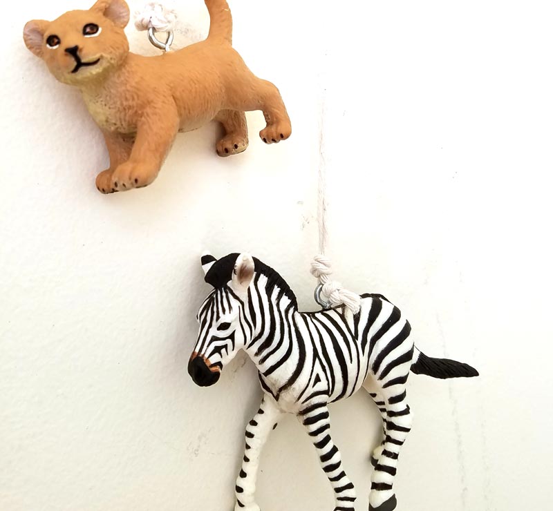 Make an adorable animal wall hanging for the kids room or nursery! Turn toy animals into beautiful playroom decor - and when your'e ready to redecorate, it can be repurposed as a toy! Love this safari animal kids bedroom decor idea - it's such an easy DIY decor craft!