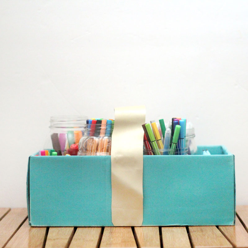 Make a super easy upcycled DIY marker storage caddy to transport the entire family's art supplies from the closet to the table in a usable bin! The jars can be removed individually to easily set up and clean up a family art station with coloring supplies for kids and adults. This recylced cardboard box and jar craft is so easy to make, and is an awesome craft room organization hack.