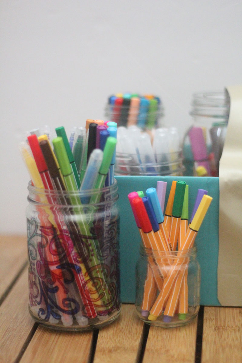 Make a super easy upcycled DIY marker storage caddy to transport the entire family's art supplies from the closet to the table in a usable bin! The jars can be removed individually to easily set up and clean up a family art station with coloring supplies for kids and adults. This recylced cardboard box and jar craft is so easy to make, and is an awesome craft room organization hack.