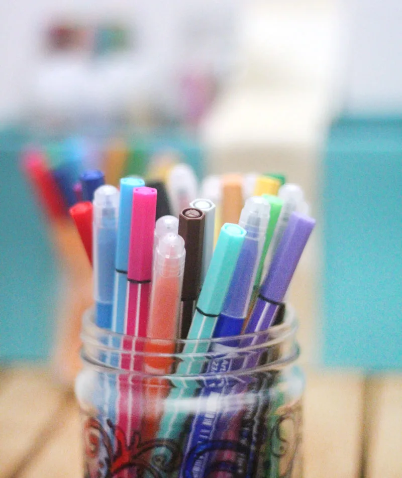 Make a super easy upcycled DIY marker storage caddy to transport the entire family's art supplies from the closet to the table in a usable bin! The jars can be removed individually to easily set up and clean up a family art station with coloring supplies for kids and adults. This recylced cardboard box and jar craft is so easy to make, and is an awesome craft room organization hack.