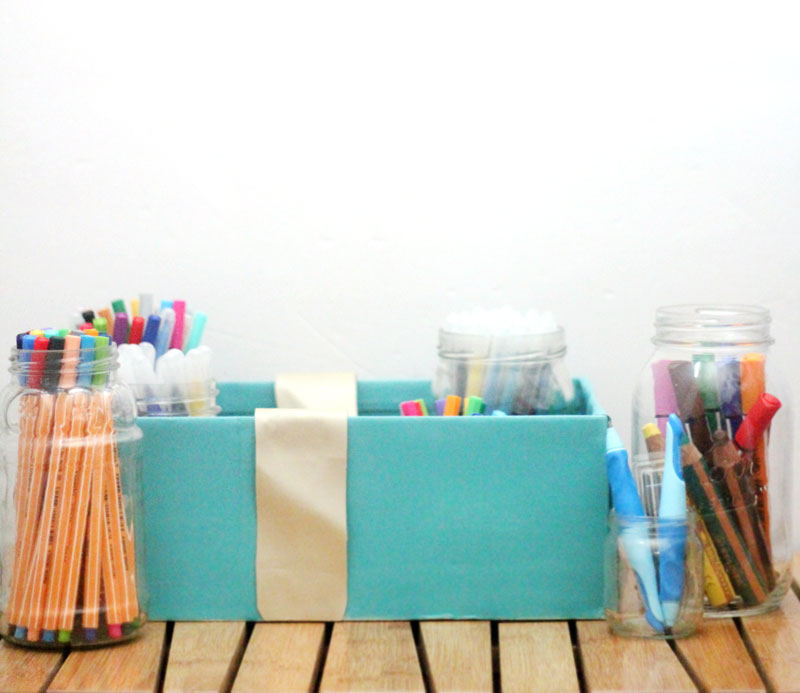 Make a super easy upcycled DIY marker storage caddy to transport the entire family's art supplies from the closet to the table in a usable bin! The jars can be removed individually to easily set up and clean up a family art station with coloring supplies for kids and adults. This recylced cardboard box and jar craft is so easy to make, and is an awesome craft room organization hack.