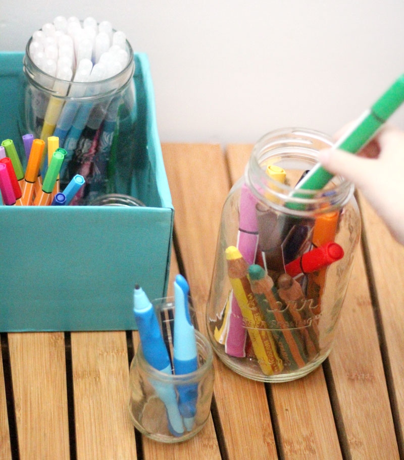 Make a super easy upcycled DIY marker storage caddy to transport the entire family's art supplies from the closet to the table in a usable bin! The jars can be removed individually to easily set up and clean up a family art station with coloring supplies for kids and adults. This recylced cardboard box and jar craft is so easy to make, and is an awesome craft room organization hack.