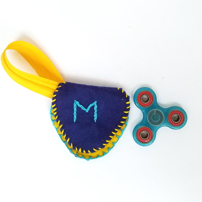 Make this DIY fidget spinner case to protect your fidget toy and keep it a bit farther out of reach of babies! It's an easy beginner felt sewing project that an adult or a child can make, plus it has a built in zipper fidget too! Free template / pattern included.