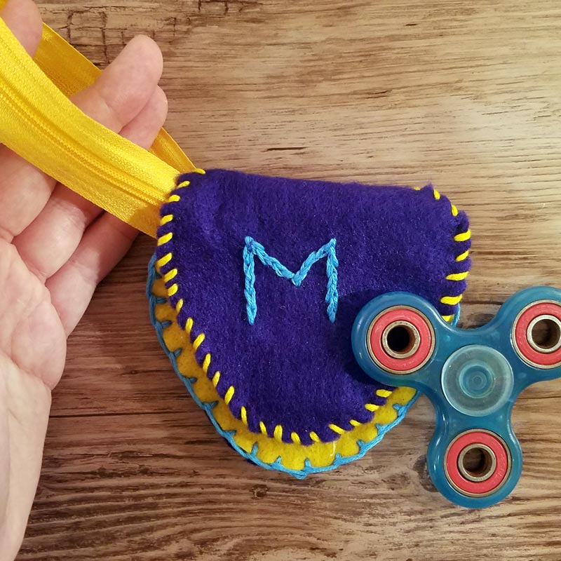 Make this DIY fidget spinner case to protect your fidget toy and keep it a bit farther out of reach of babies! It's an easy beginner felt sewing project that an adult or a child can make, plus it has a built in zipper fidget too! Free template / pattern included.