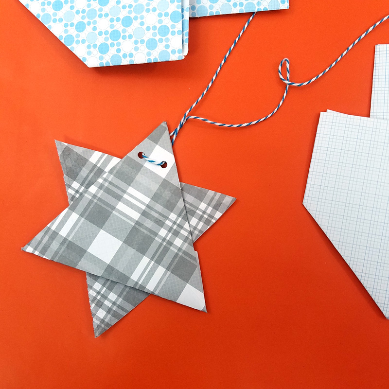 Make a fun origami Hanukkah garland featuring folded paper dreidels and star of david. This simple Chanukah craft for kids teens and adults is a perfect way to update your Hanukkah decor.