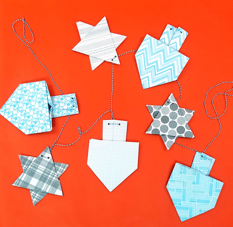 Make a fun origami Hanukkah garland featuring folded paper dreidels and star of david. This simple Chanukah craft for kids teens and adults is a perfect way to update your Hanukkah decor.