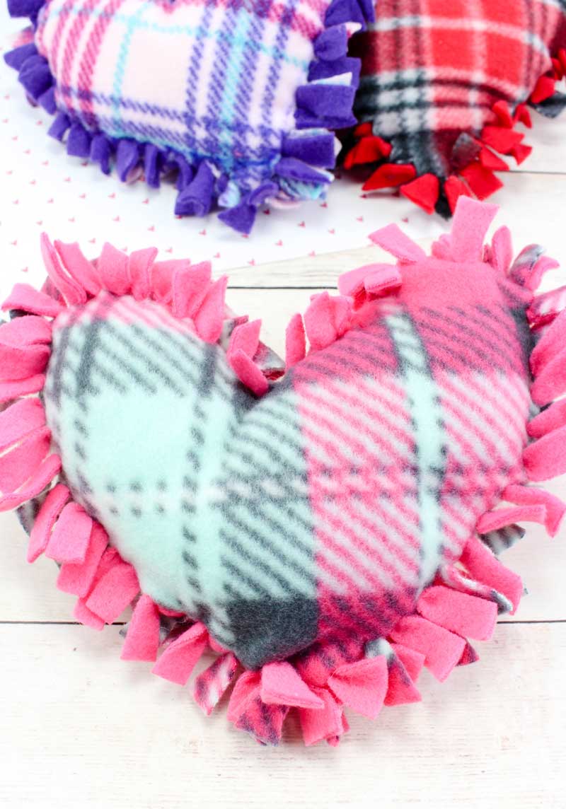 These valentine pillows are so easy to make! They use the classic summer camp fleece tie pillows method and are the perfect Valentine's Day crafts for tweens and big kids. #tweens #teencrafts #valentinesday