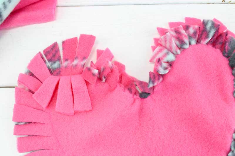 These valentine pillows are so easy to make! They use the classic summer camp fleece tie pillows method and are the perfect Valentine's Day crafts for tweens and big kids. #tweens #teencrafts #valentinesday