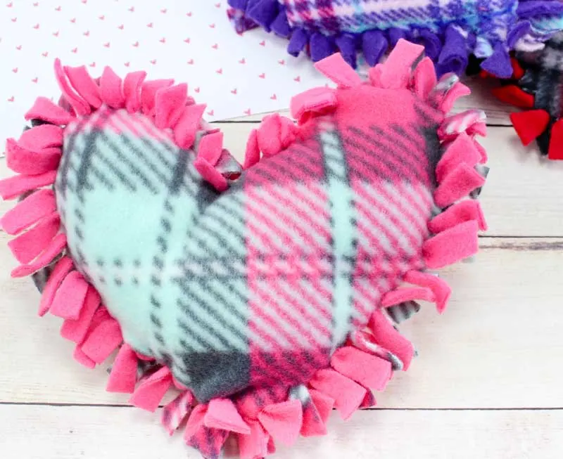 These valentine pillows are so easy to make! They use the classic summer camp fleece tie pillows method and are the perfect Valentine's Day crafts for tweens and big kids. #tweens #teencrafts #valentinesday
