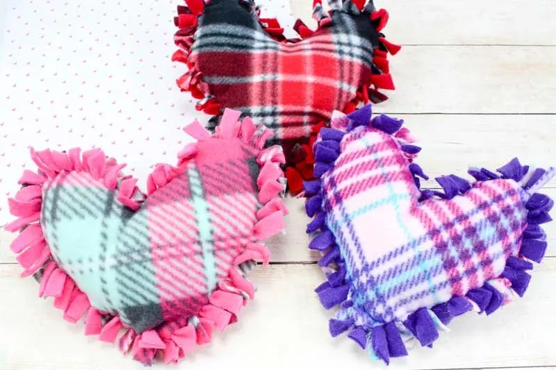 These valentine pillows are so easy to make! They use the classic summer camp fleece tie pillows method and are the perfect Valentine's Day crafts for tweens and big kids. #tweens #teencrafts #valentinesday