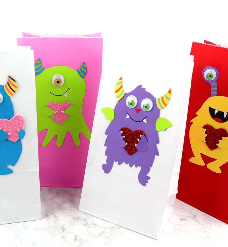 These adorable Monster love valentine treat bags are perfect for favors or snacks! This cute Valentine's Day paper craft is also good for a monster birhtday party. It doesn't have to have the heart, and you can put any shape in the monster's hands. #papercraft #valentinesday #valentine