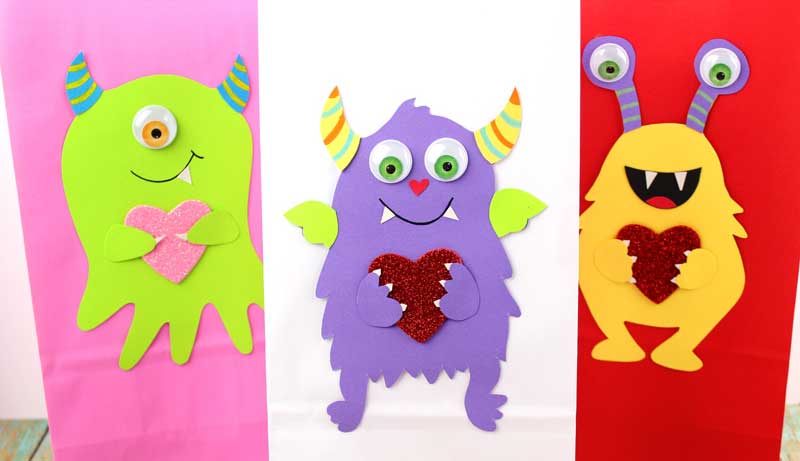 These adorable Monster love valentine treat bags are perfect for favors or snacks! This cute Valentine's Day paper craft is also good for a monster birhtday party. It doesn't have to have the heart, and you can put any shape in the monster's hands. #papercraft #valentinesday #valentine