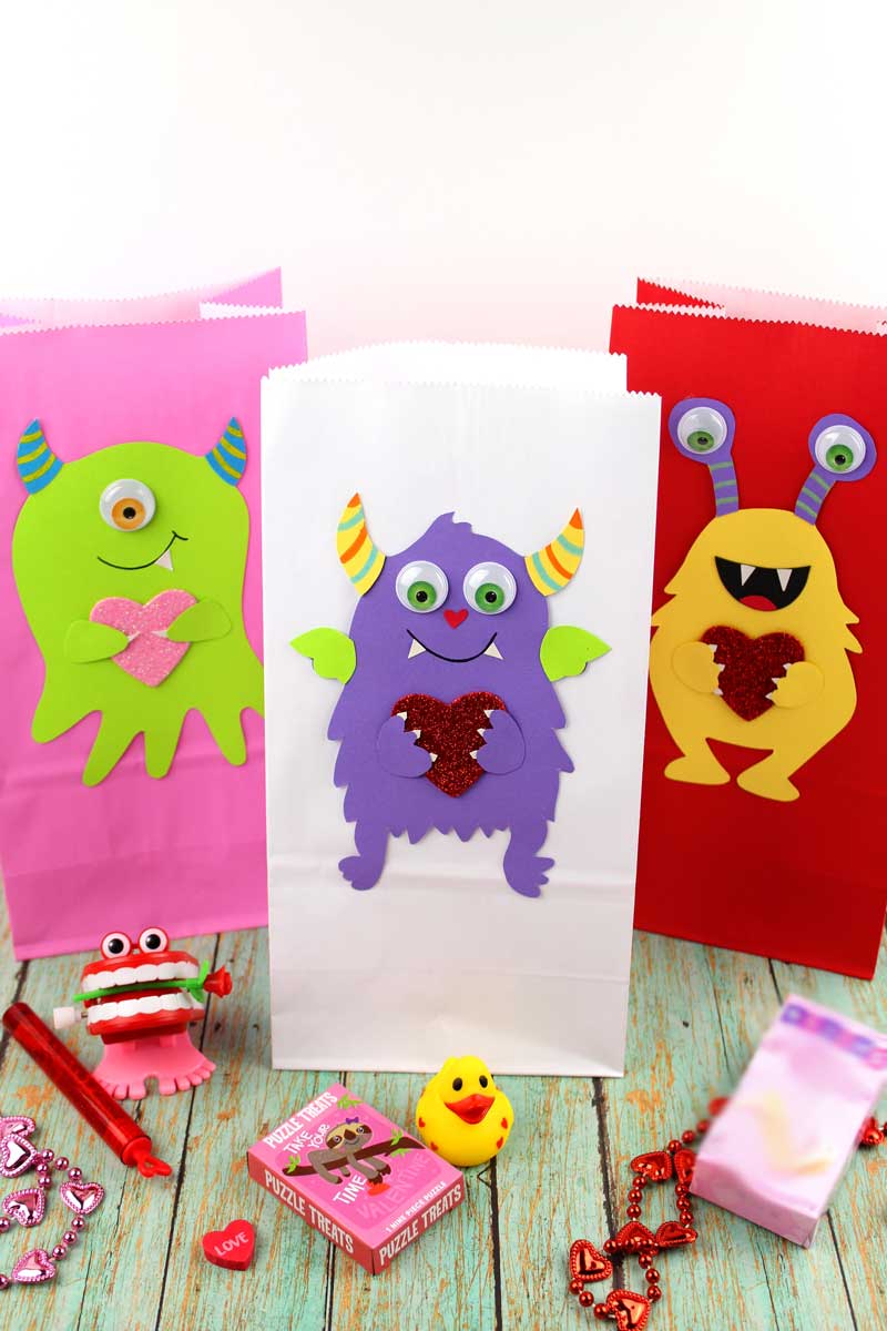 These adorable Monster love valentine treat bags are perfect for favors or snacks! This cute Valentine's Day paper craft is also good for a monster birhtday party. It doesn't have to have the heart, and you can put any shape in the monster's hands. #papercraft #valentinesday #valentine