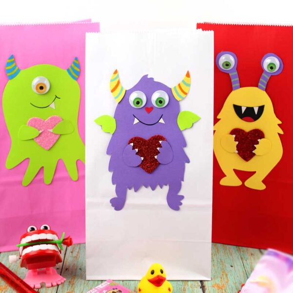 These adorable Monster love valentine treat bags are perfect for favors or snacks! This cute Valentine's Day paper craft is also good for a monster birhtday party. It doesn't have to have the heart, and you can put any shape in the monster's hands. #papercraft #valentinesday #valentine