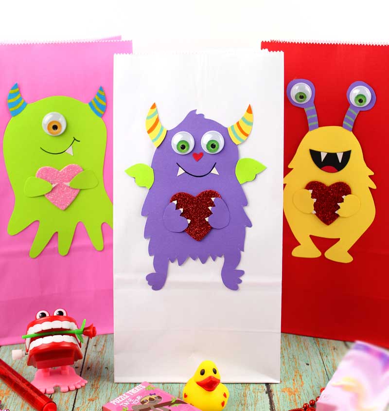 These adorable Monster love valentine treat bags are perfect for favors or snacks! This cute Valentine's Day paper craft is also good for a monster birhtday party. It doesn't have to have the heart, and you can put any shape in the monster's hands. #papercraft #valentinesday #valentine