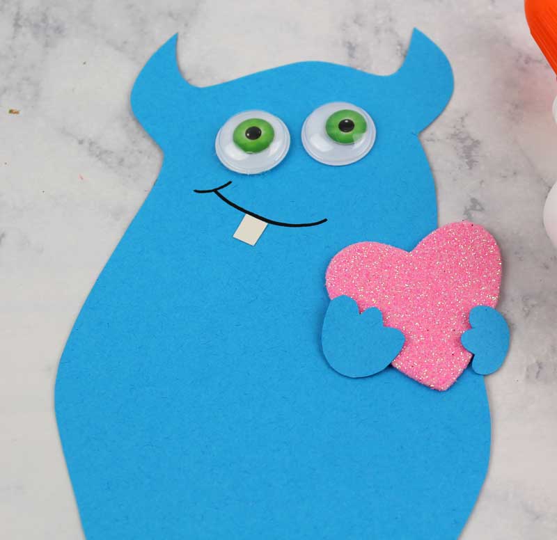 These adorable Monster love valentine treat bags are perfect for favors or snacks! This cute Valentine's Day paper craft is also good for a monster birhtday party. It doesn't have to have the heart, and you can put any shape in the monster's hands. #papercraft #valentinesday #valentine