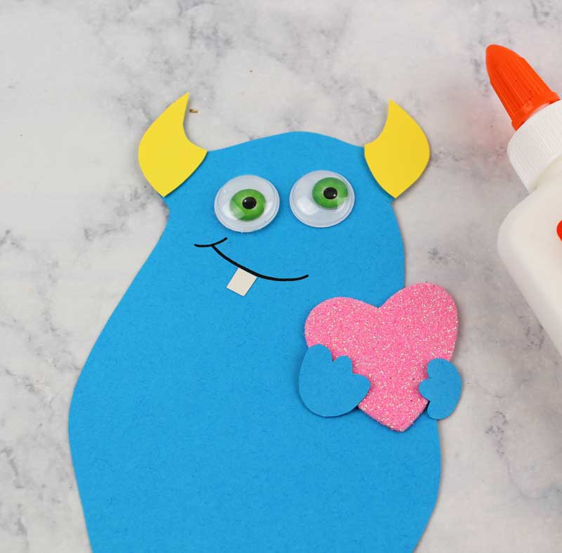 These adorable Monster love valentine treat bags are perfect for favors or snacks! This cute Valentine's Day paper craft is also good for a monster birhtday party. It doesn't have to have the heart, and you can put any shape in the monster's hands. #papercraft #valentinesday #valentine