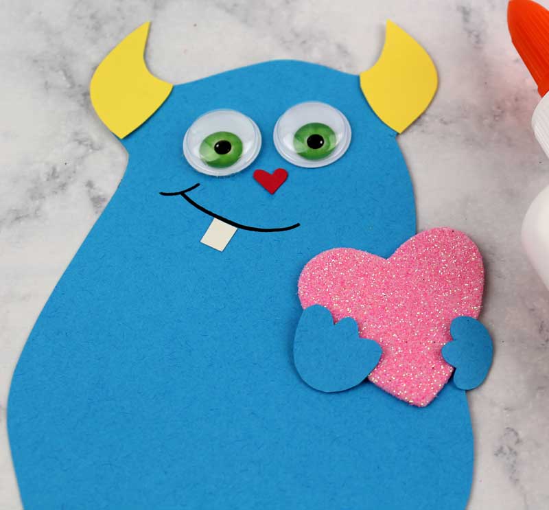 These adorable Monster love valentine treat bags are perfect for favors or snacks! This cute Valentine's Day paper craft is also good for a monster birhtday party. It doesn't have to have the heart, and you can put any shape in the monster's hands. #papercraft #valentinesday #valentine