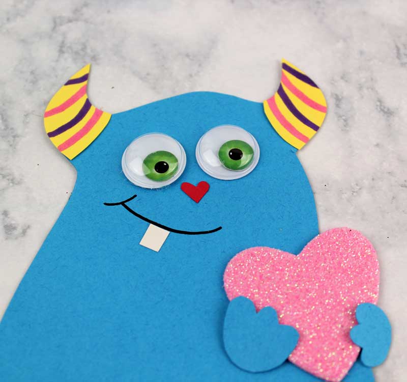 These adorable Monster love valentine treat bags are perfect for favors or snacks! This cute Valentine's Day paper craft is also good for a monster birhtday party. It doesn't have to have the heart, and you can put any shape in the monster's hands. #papercraft #valentinesday #valentine