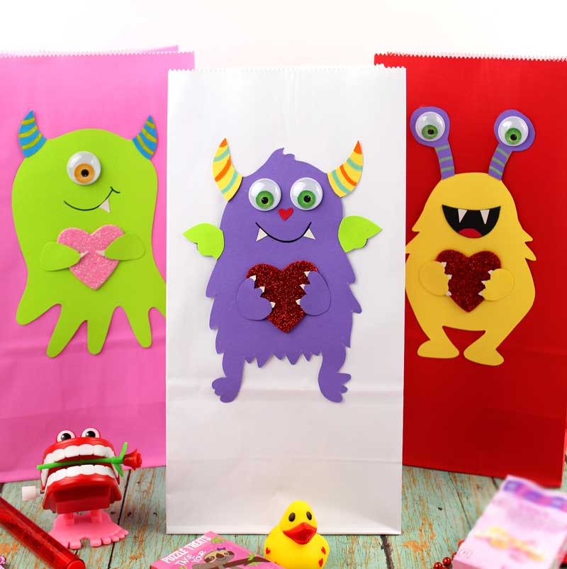 These adorable Monster love valentine treat bags are perfect for favors or snacks! This cute Valentine's Day paper craft is also good for a monster birhtday party. It doesn't have to have the heart, and you can put any shape in the monster's hands. #papercraft #valentinesday #valentine