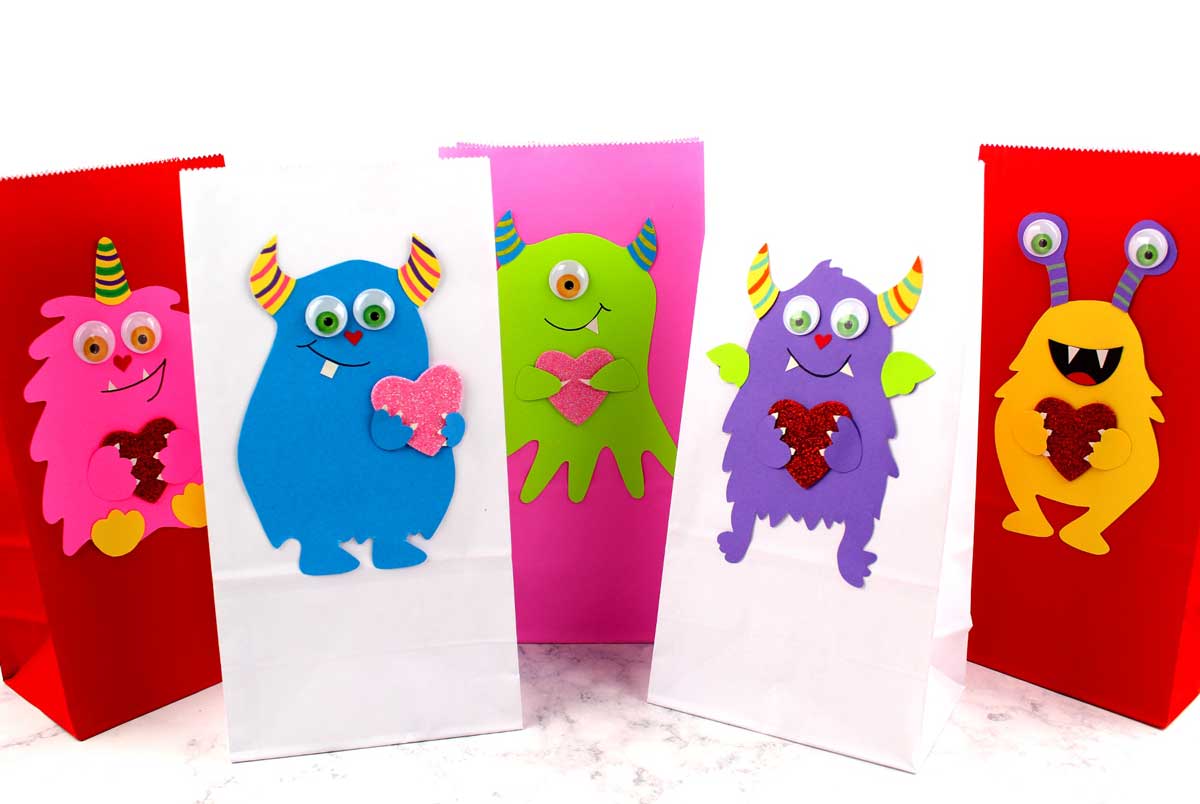 These adorable Monster love valentine treat bags are perfect for favors or snacks! This cute Valentine's Day paper craft is also good for a monster birhtday party. It doesn't have to have the heart, and you can put any shape in the monster's hands. #papercraft #valentinesday #valentine