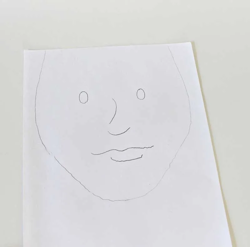 Step 1. Use the pen to draw a face on the piece of white paper. From the top of the forehead to the chin should be about 8 inches. From the top of the forehead to the middle of the eyes should be about 3 inches.